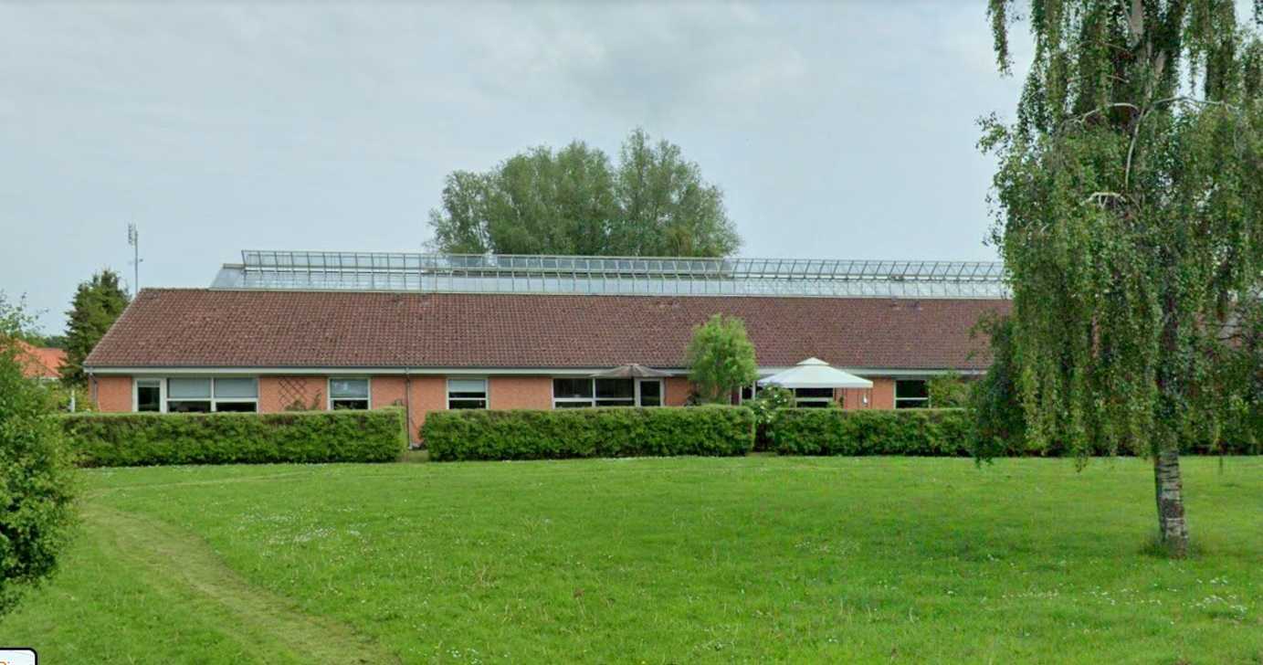 Ældrebolig Perlen. Der er en masse grønt græs. Bygningen er rød.