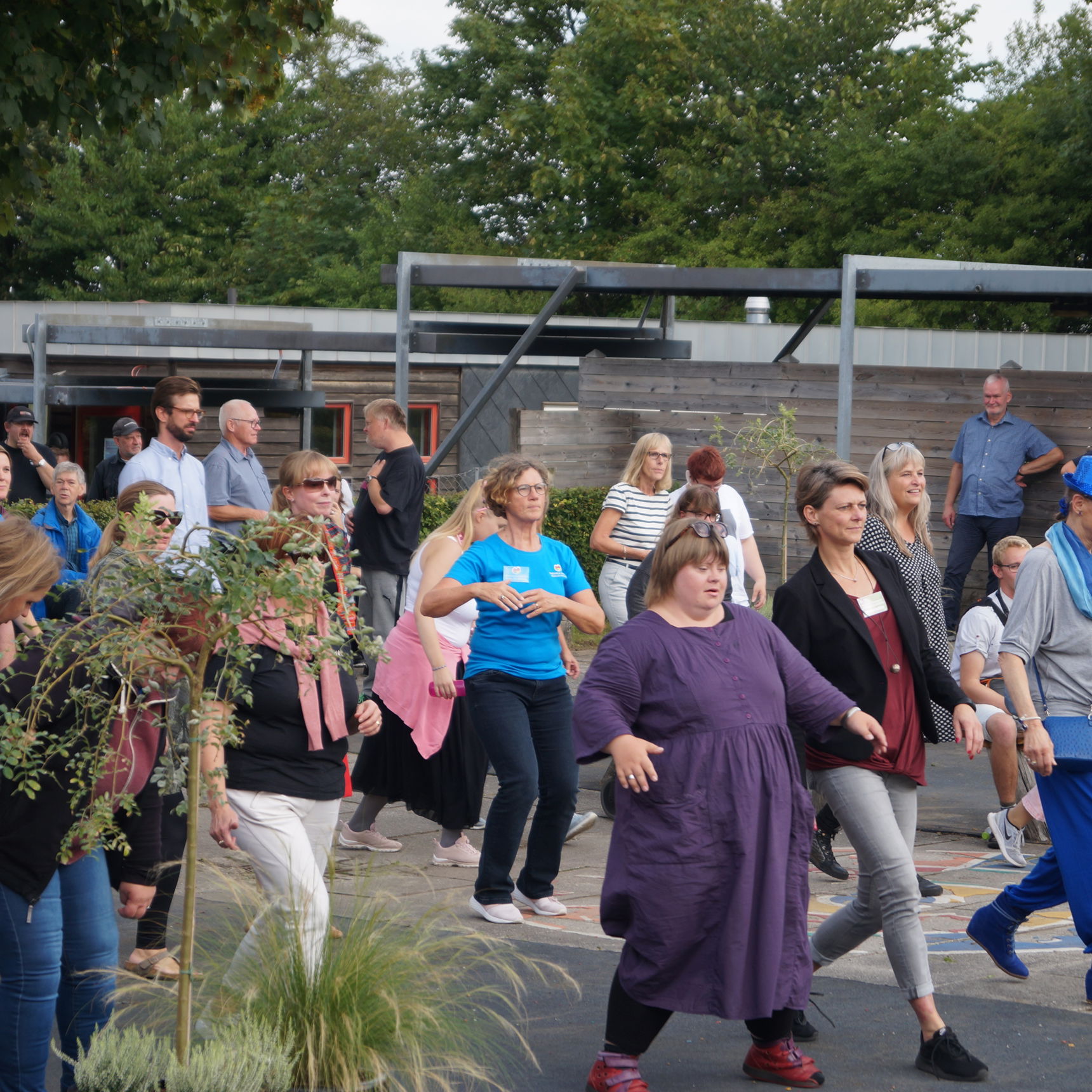 En masse mennesker, der danser en fælles dans. De smiler og er glade.