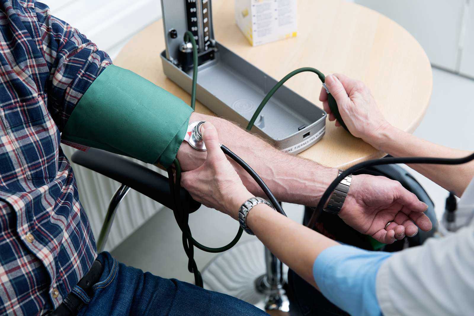 Læge tager blodtrykket på en patient.