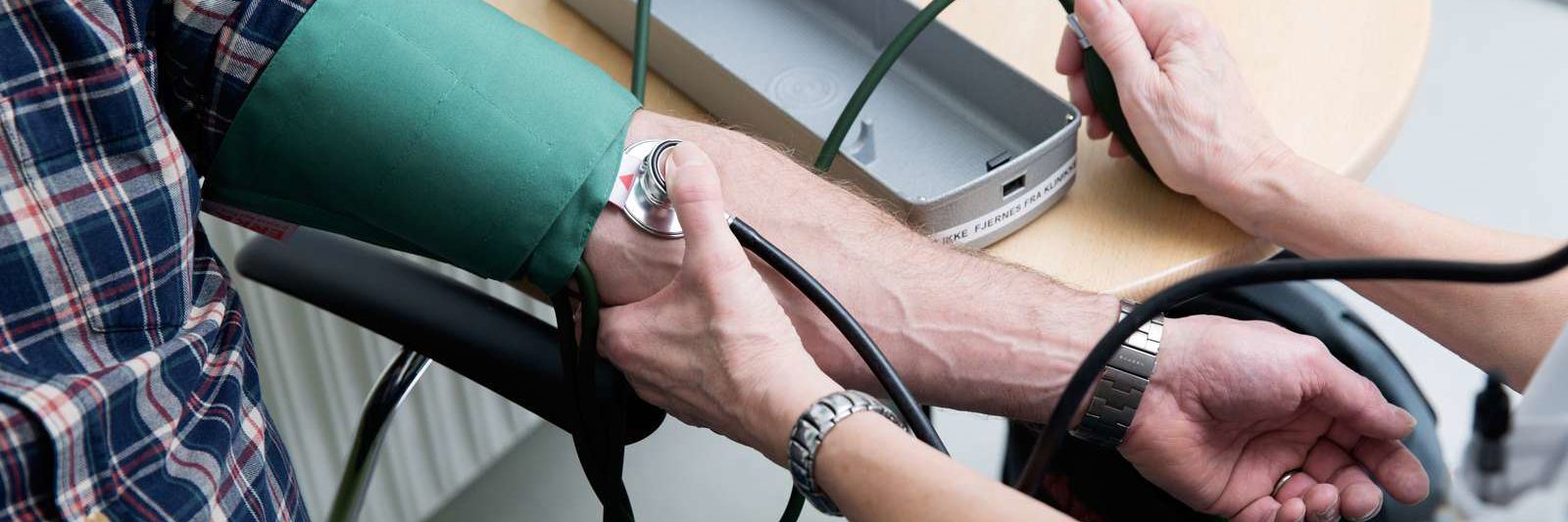 Læge tager blodtrykket på en patient.