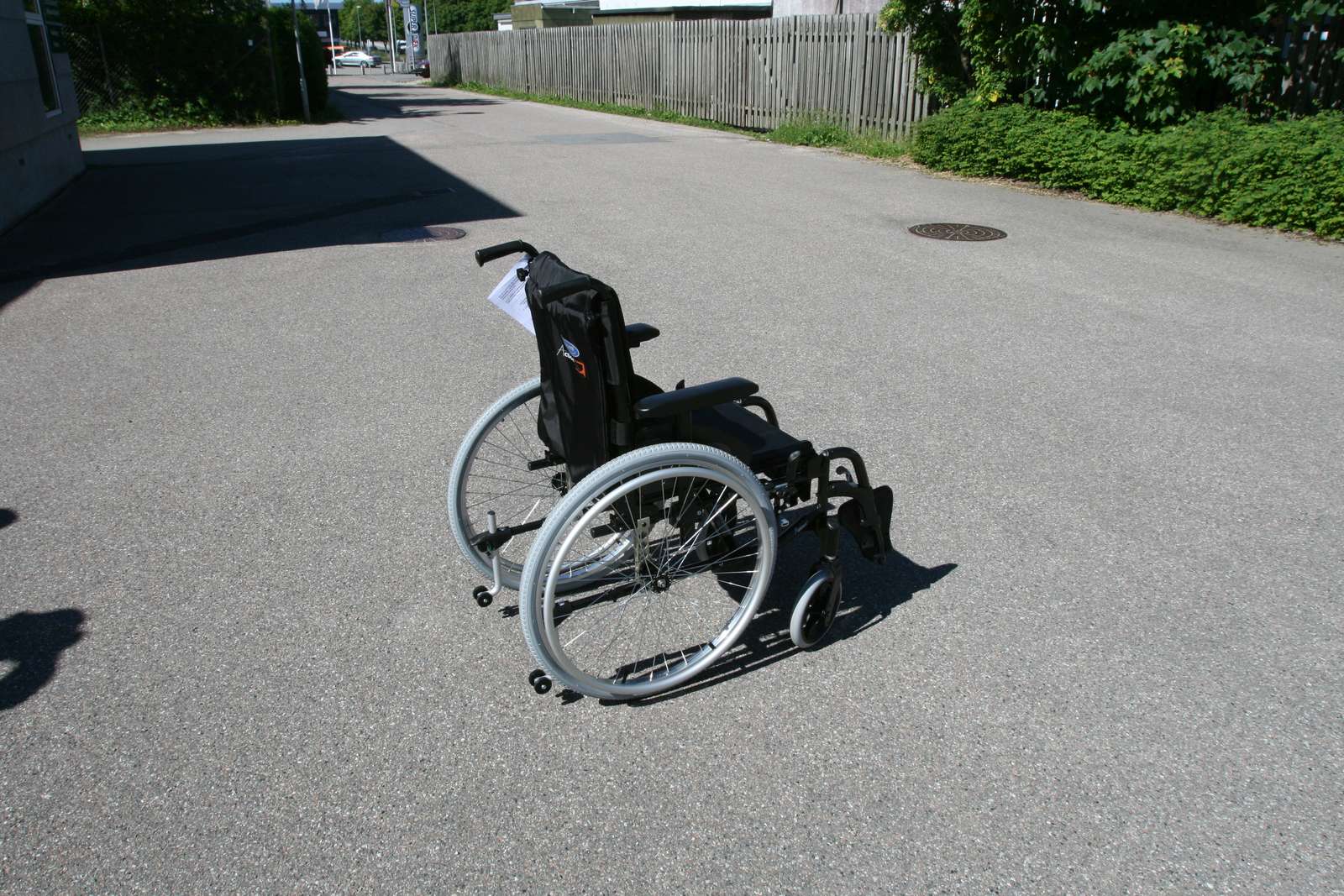 En kørestol uden ejermand. Den står udenfor på asfalten.