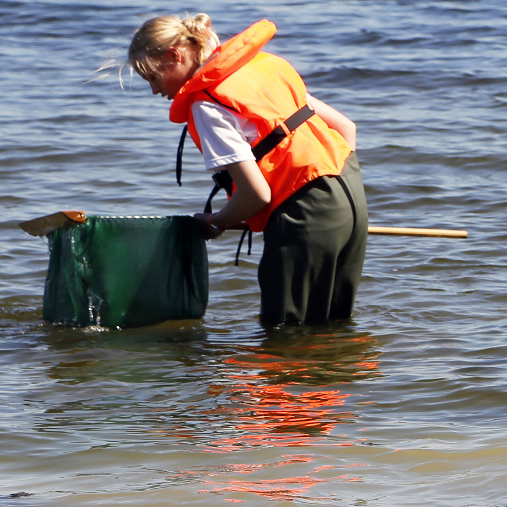 Tre elever med waders fisker med ketsjer i fjorden