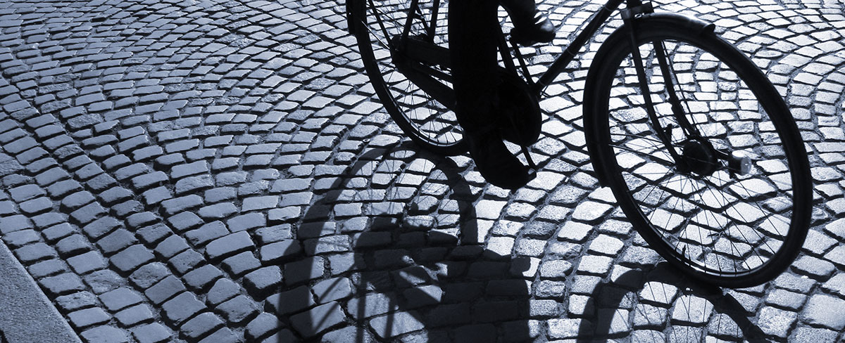Nederste del af en cykel, der cykler på brosten.