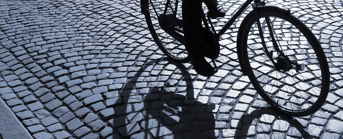 Nederste del af en cykel, der cykler på brosten.