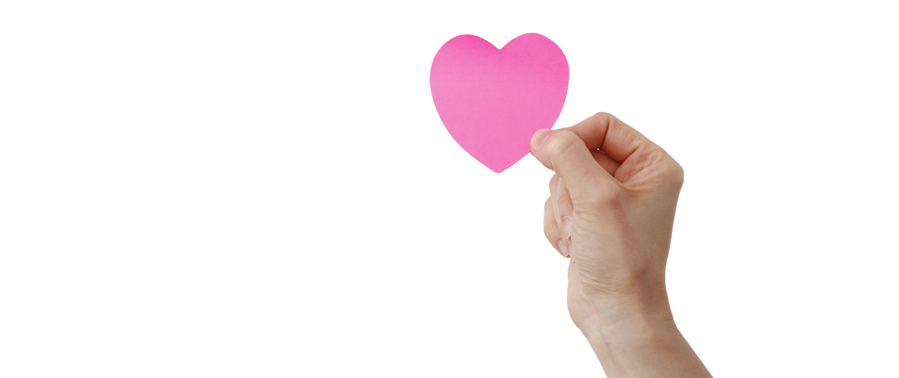 En hånd, der holder et lyserødt papirhjerte mellem tommel- og pegefinger. Baggrunden er helt hvid.