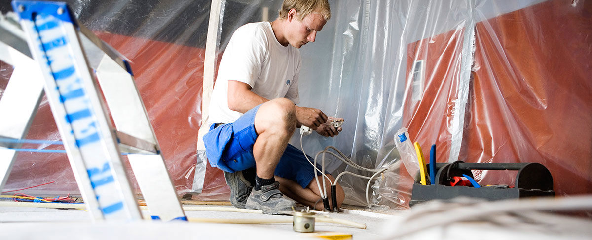 Elektriker fikser ledninger i bygning.