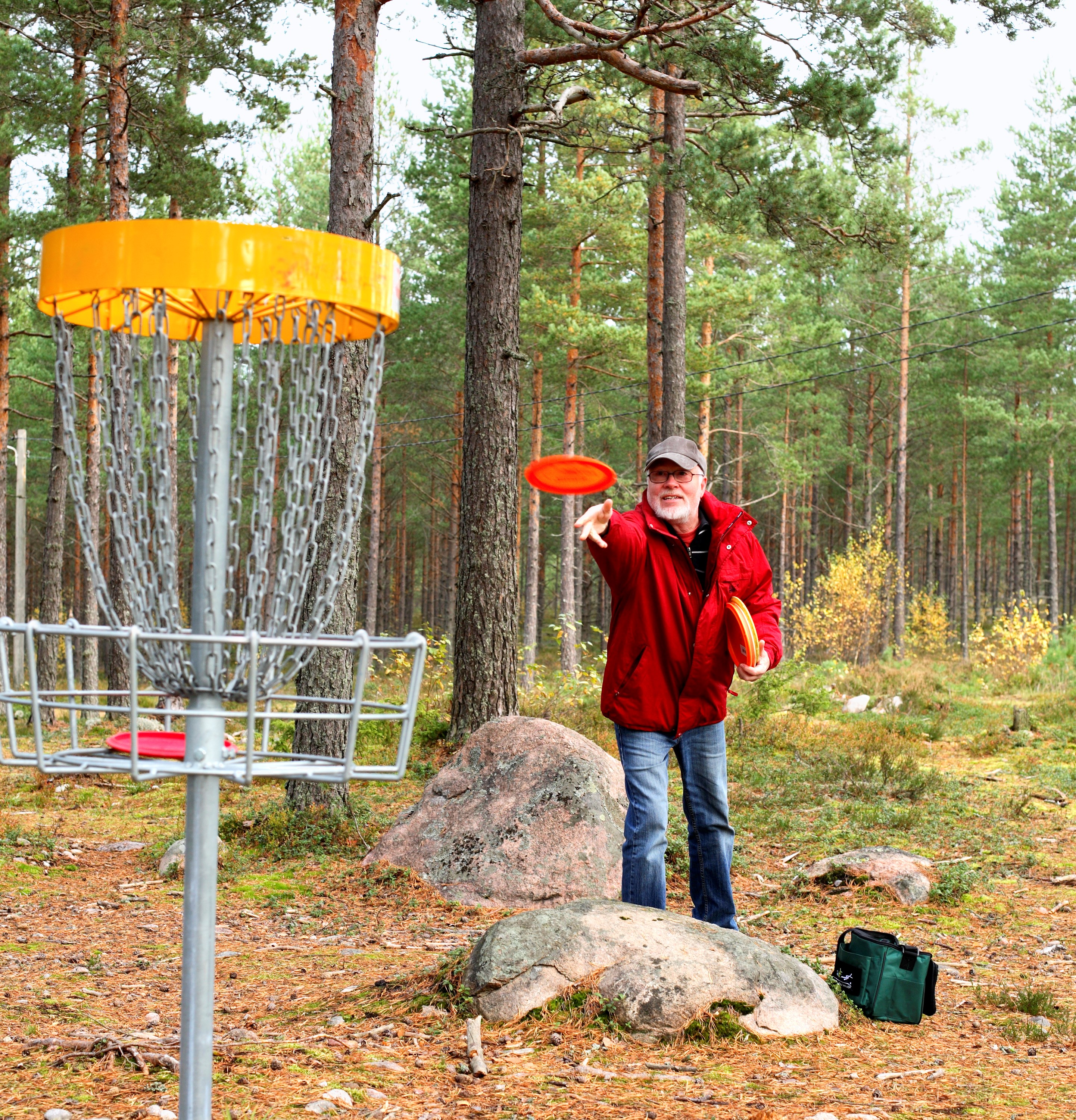 Mand kaster en frisbee. Han spiller discgolf.